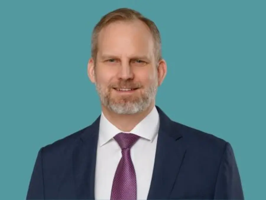 Portrait Dr. Christian Saueressig mit blonden kurzen Haare, Bart, dunkelblauem Sakko, wei&szlig;em Hemd und lila Krawatte