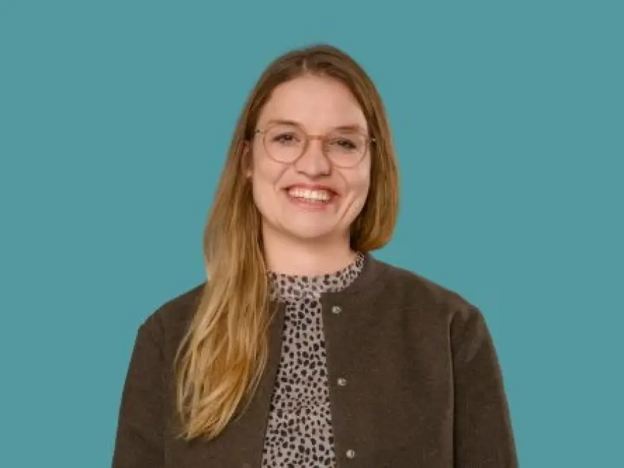 Portrait Katharina Reindl, lange dinkelblonde Haare, Brille, dunkelbraune Jacke